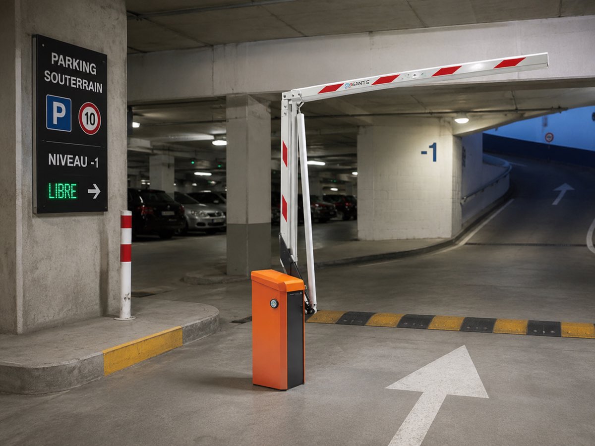 Barriere levante a lisse rouge et blanche avec coffret orange, controle d'acces a l'entree d'un parking souterrain.